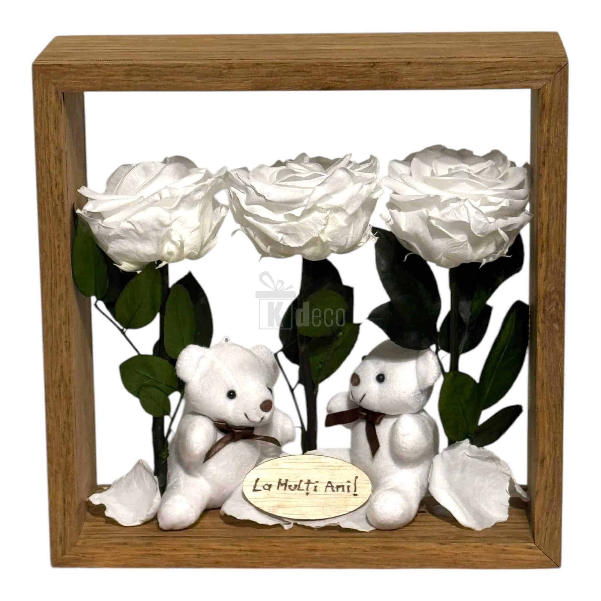 Aranjament de masă cu 3 trandafiri criogenați albi, 2 ursuleți de plus și mesaj personalizat 'La Mulți Ani' în ramă din plexiglas 27x27cm.