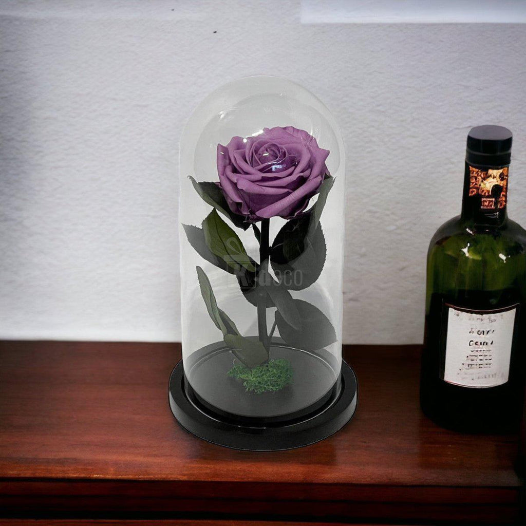 Trandafir Criogenat Lila în cupolă de sticlă, expus pe mobilier clasic lângă o sticlă de vin, cadou rafinat pentru doamne.